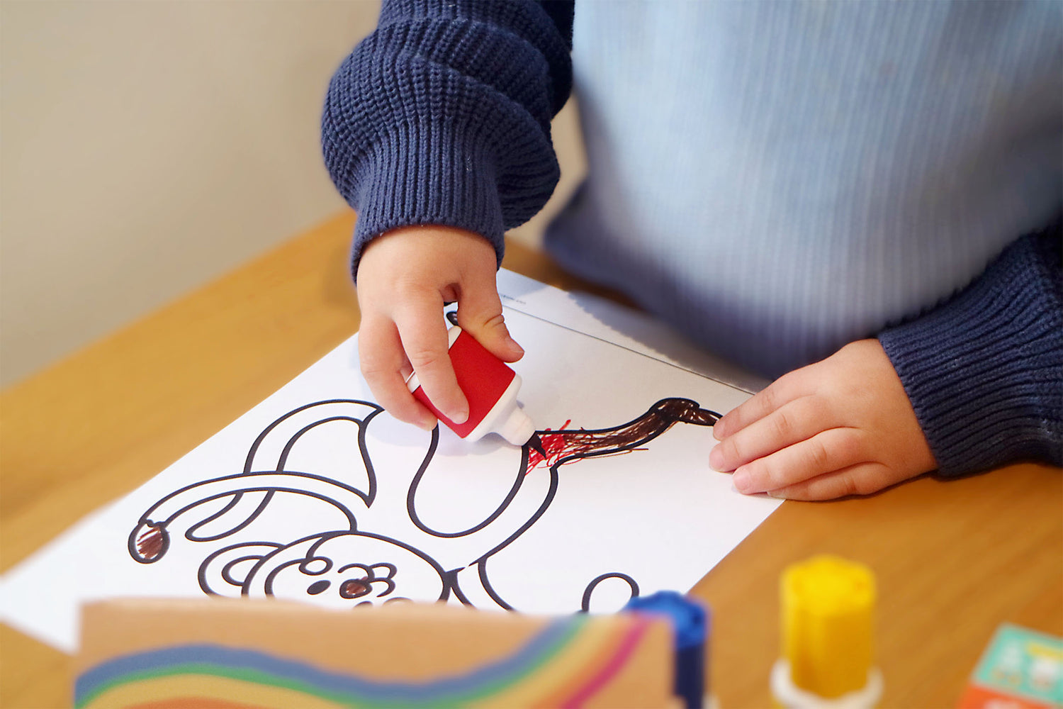A child holding Sunny Marker and colouring in a picture