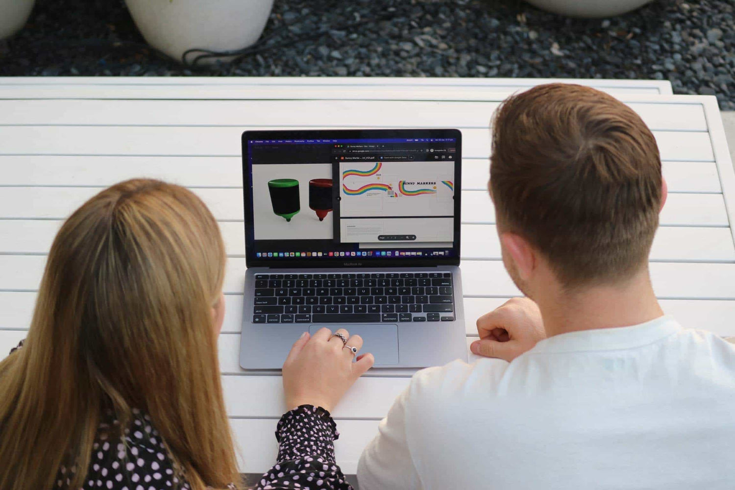 Two people looking at a laptop screen with makers displayed